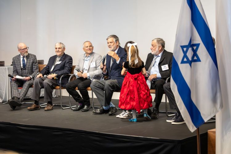 Jed Margolis talks with full panel and Israeli flag foreground