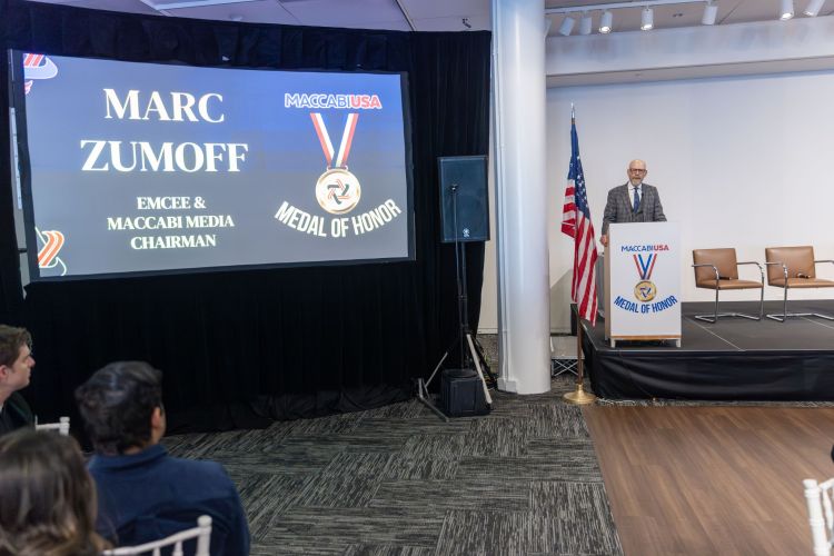 Marc Zumoff on stage with name graphic