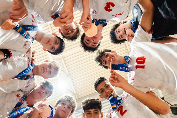 GREAT GOD SHOT looking up from inside huddle U17 Boys' Futsal with medals DSC04545